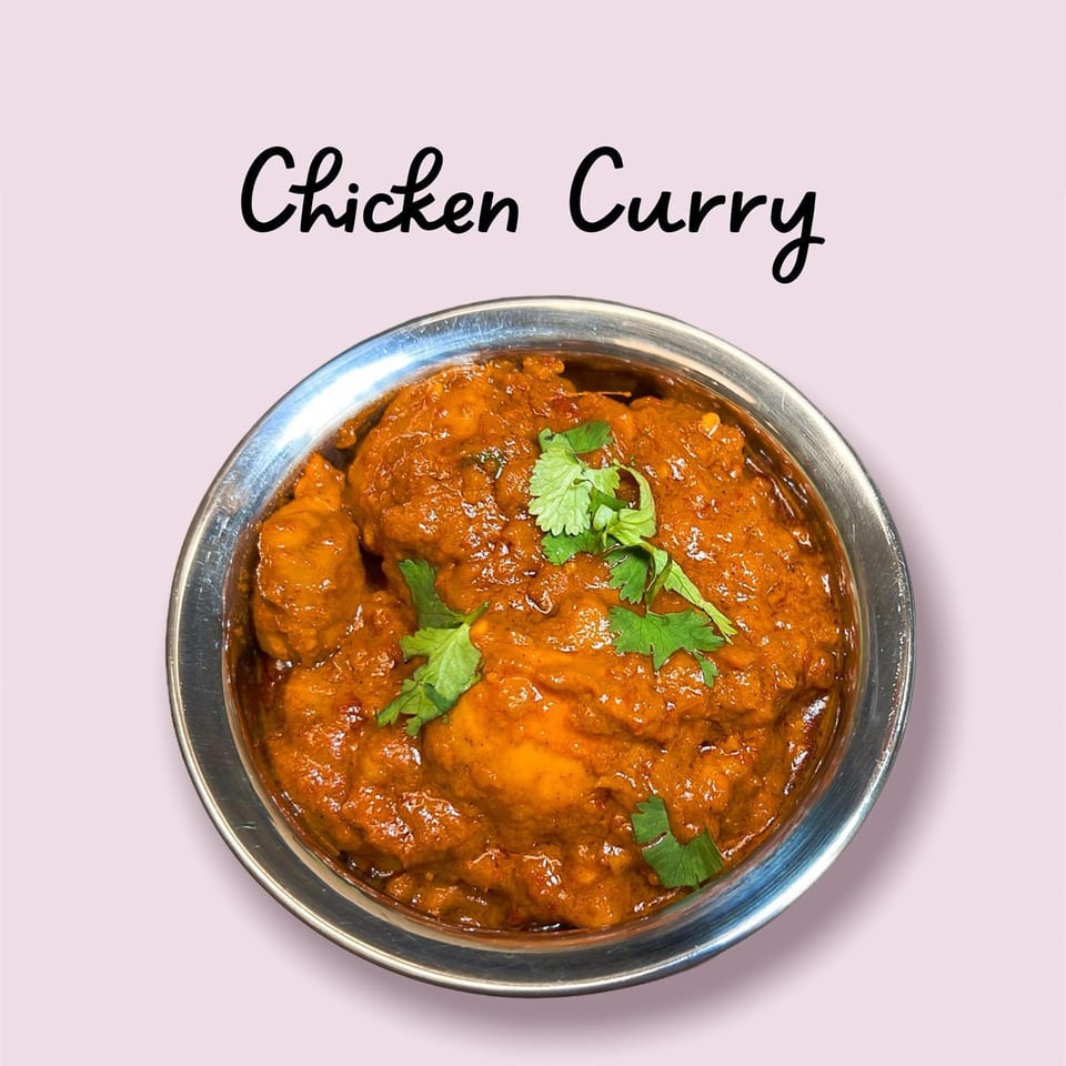 Namaste Curry Lounge's Indian Chicken Curry, a rich orange dish garnished with fresh cilantro in a metal bowl.