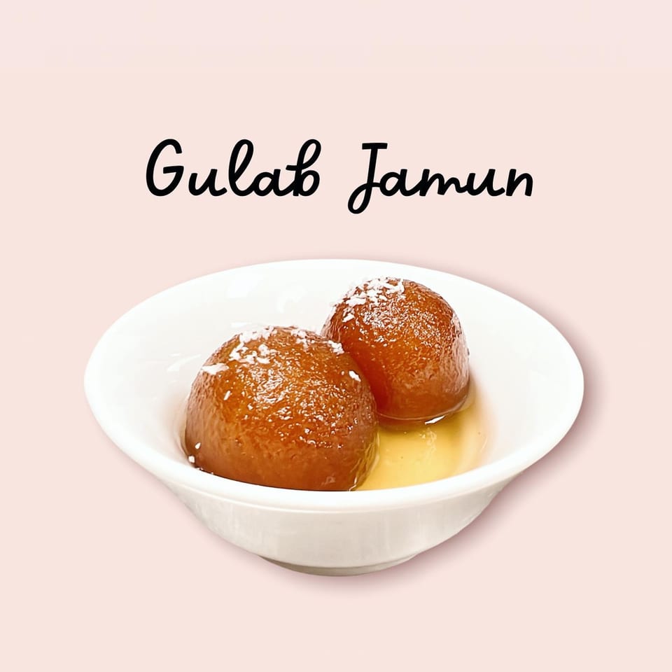 Two Gulab Jamun, Indian fried dough balls in syrup, topped with coconut flakes in a white bowl.