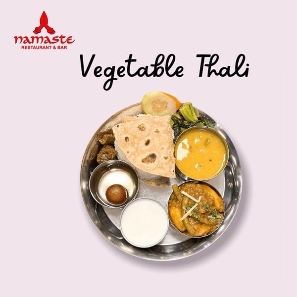 A Namaste Curry Lounge Vegetable Thali with various Indian dishes, rice, and flatbread.