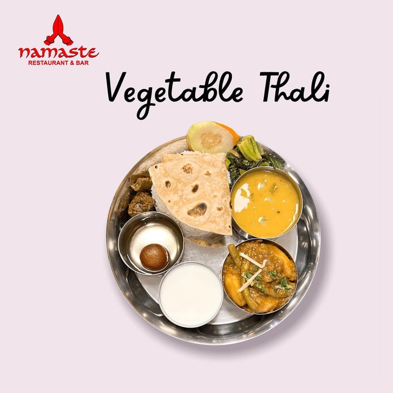 A Namaste Curry Lounge Vegetable Thali with various Indian dishes, rice, and flatbread.